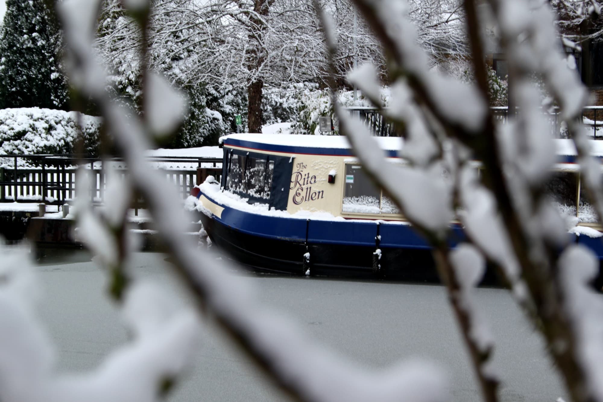 The Rita Ellen moored at Stratford under snow, her name painted on the cream cabin
