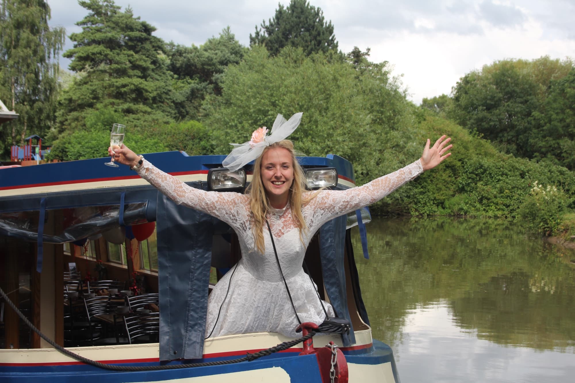 A guest raising a glass of fizz on the bow of The Rita Ellen